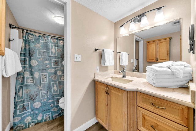 bathroom with hardwood / wood-style floors, vanity, a shower with shower curtain, toilet, and a textured ceiling