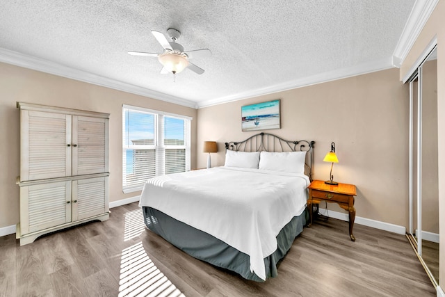 bedroom featuring ceiling fan, wood-type flooring, ornamental molding, and a closet