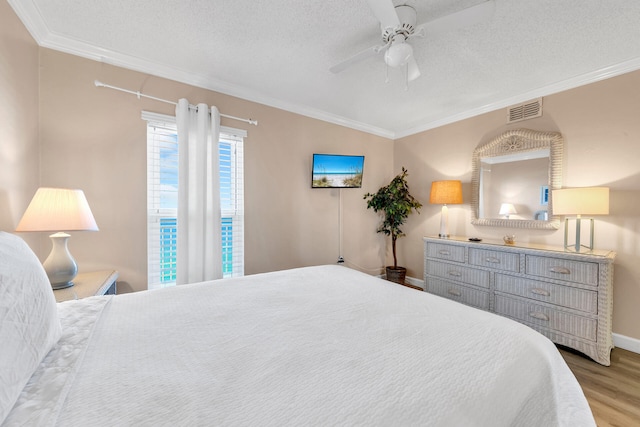 bedroom featuring hardwood / wood-style floors, vaulted ceiling, ceiling fan, ornamental molding, and a textured ceiling