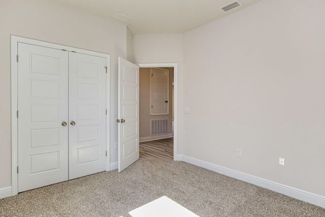 unfurnished bedroom featuring light carpet and a closet