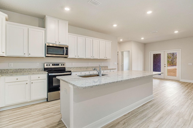 kitchen featuring white cabinetry, sink, stainless steel appliances, and a center island with sink