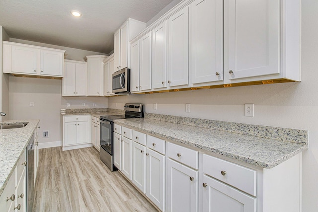 kitchen with white cabinets, light stone countertops, sink, and stainless steel appliances