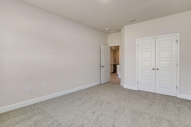 unfurnished bedroom featuring carpet, a textured ceiling, and a closet