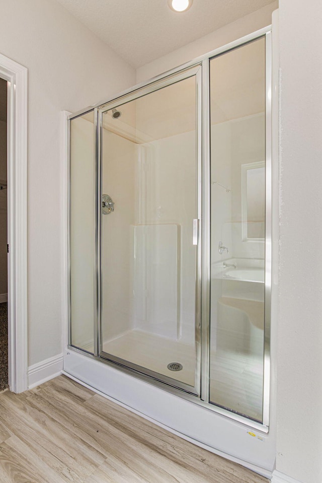 bathroom with hardwood / wood-style flooring and a shower with shower door