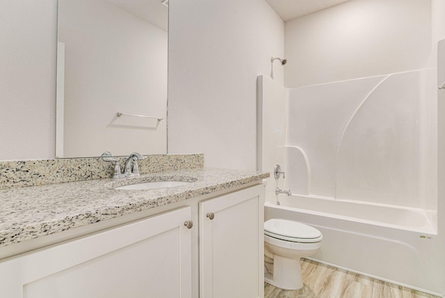 full bathroom with washtub / shower combination, hardwood / wood-style floors, a textured ceiling, toilet, and vanity