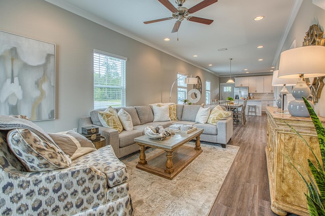 living room with ceiling fan, light wood-type flooring, and ornamental molding