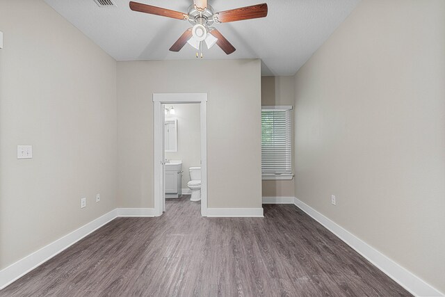 182 N Sand Palm Rd, Freeport, FL 32439 - unfurnished bedroom featuring dark wood-style floors, baseboards, ensuite bath, and ceiling fan