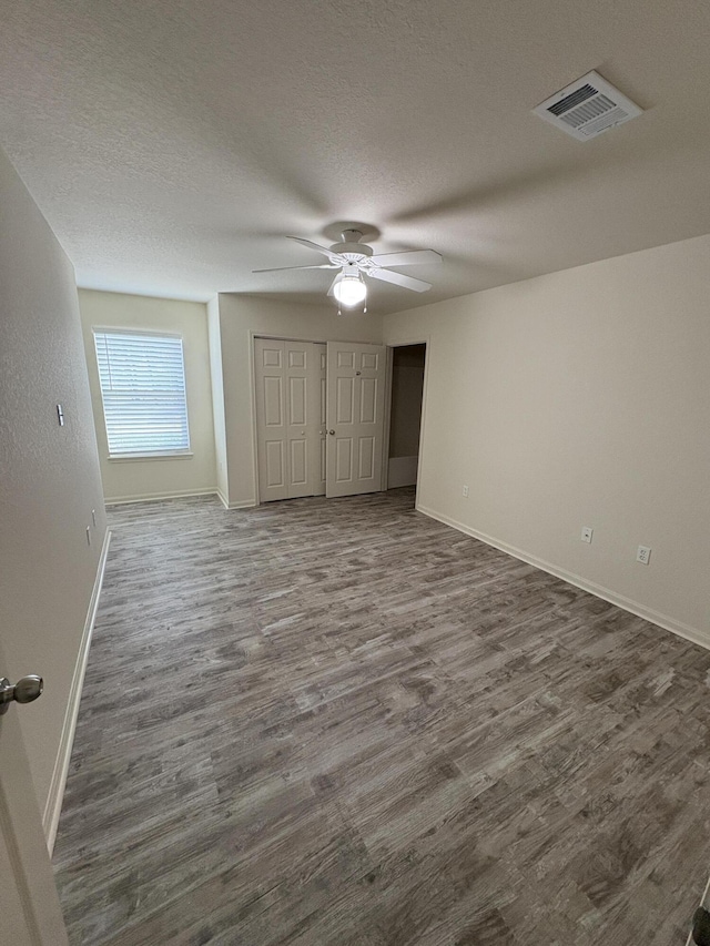 unfurnished bedroom featuring ceiling fan, dark hardwood / wood-style flooring, and a textured ceiling