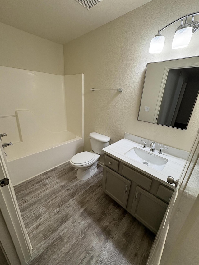 full bathroom featuring bathtub / shower combination, wood-type flooring, vanity, and toilet