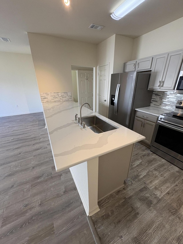 kitchen featuring backsplash, sink, stainless steel appliances, and dark wood-type flooring