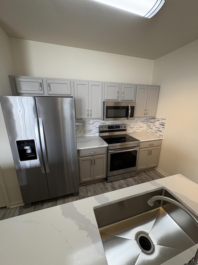 kitchen with tasteful backsplash, gray cabinets, sink, and stainless steel appliances