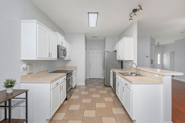 kitchen with kitchen peninsula, sink, appliances with stainless steel finishes, white cabinetry, and a breakfast bar area