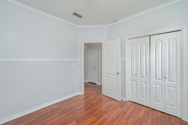 unfurnished bedroom with dark hardwood / wood-style floors, a closet, and ornamental molding