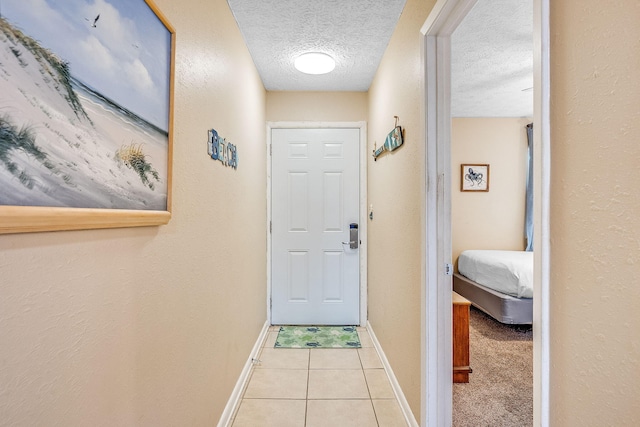 doorway to outside featuring light tile patterned floors and a textured ceiling