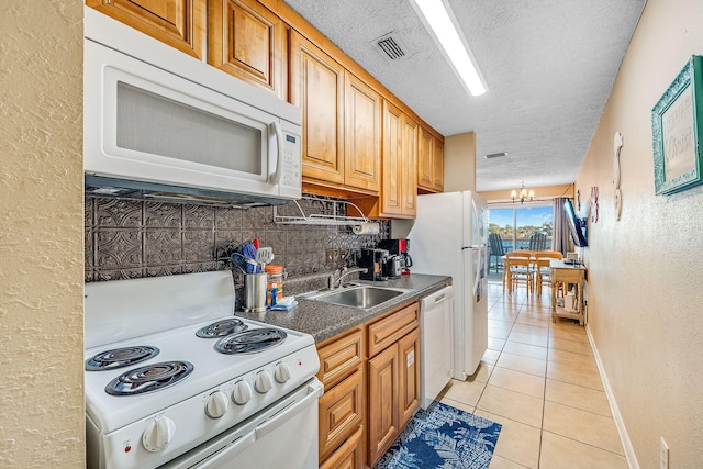 kitchen with white appliances, a textured ceiling, sink, light tile patterned floors, and an inviting chandelier