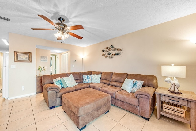 living room with ceiling fan, light tile patterned floors, and a textured ceiling