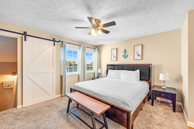 carpeted bedroom featuring a textured ceiling, a barn door, a water view, and ceiling fan