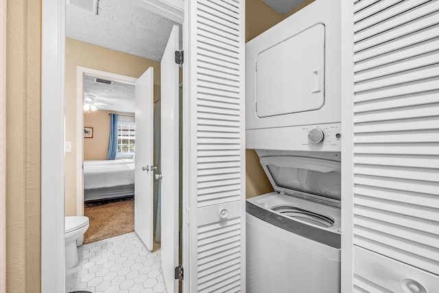 laundry room with light carpet, a textured ceiling, stacked washer and dryer, and ceiling fan