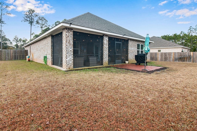 rear view of house with a sunroom, a patio, and a lawn