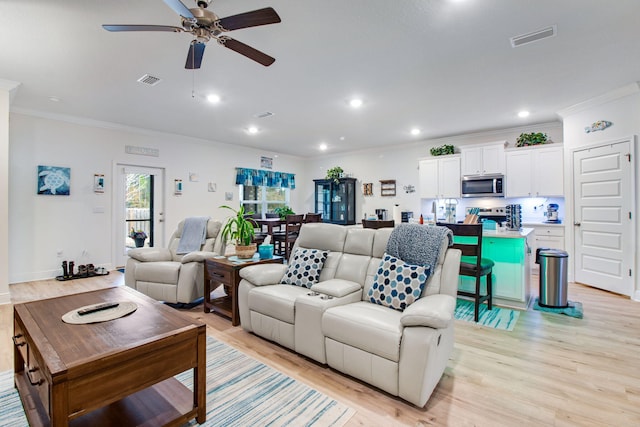 living room with light hardwood / wood-style flooring, ceiling fan, and crown molding