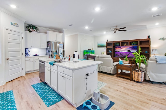 kitchen with stainless steel appliances, a kitchen island with sink, ceiling fan, sink, and white cabinets