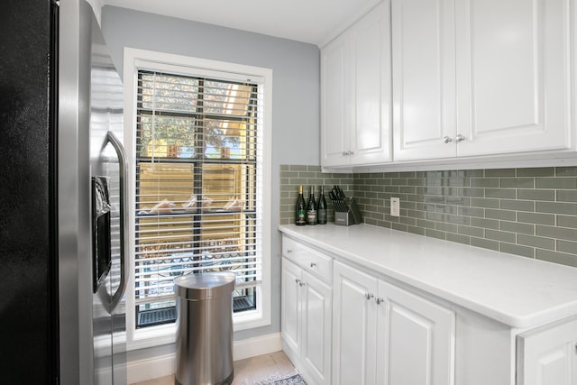 kitchen with decorative backsplash, a healthy amount of sunlight, white cabinetry, and fridge with ice dispenser