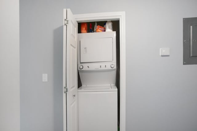 laundry room featuring electric panel and stacked washing maching and dryer