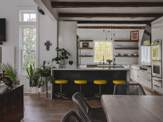 bar featuring white cabinets, beamed ceiling, a healthy amount of sunlight, and decorative light fixtures