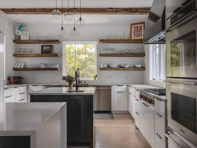 kitchen with white cabinets, hanging light fixtures, appliances with stainless steel finishes, tasteful backsplash, and a kitchen island