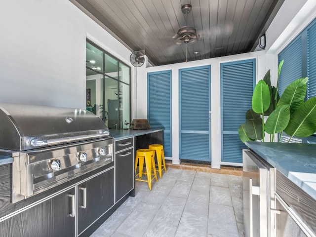 view of patio featuring ceiling fan, an outdoor kitchen, a grill, wine cooler, and exterior bar