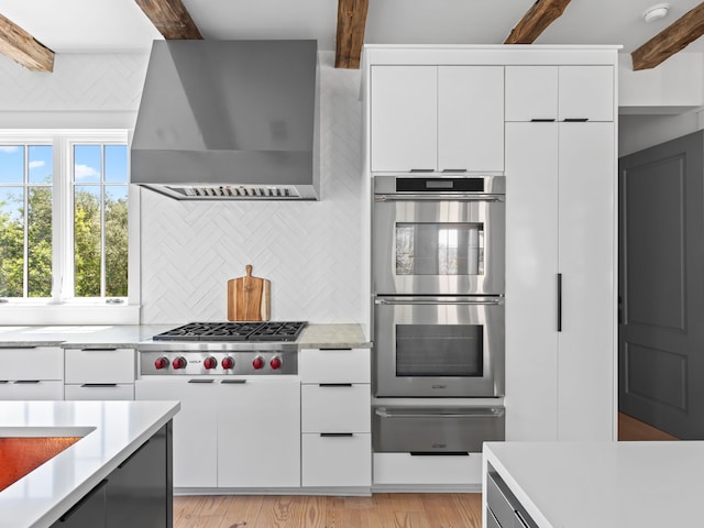 107 E Bermuda Dr, Santa Rosa Beach, FL 32459 - kitchen with a warming drawer, wall chimney exhaust hood, stainless steel appliances, light countertops, and beamed ceiling