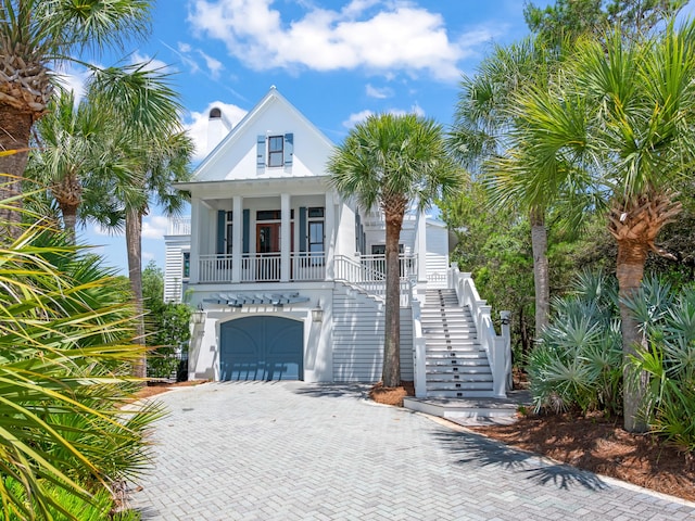107 E Bermuda Dr, Santa Rosa Beach, FL 32459 - raised beach house featuring stairs, a porch, decorative driveway, a garage, and stucco siding