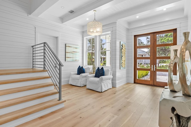 living area with plenty of natural light, light hardwood / wood-style flooring, beam ceiling, and french doors