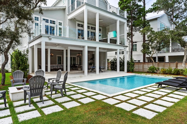 back of property featuring a balcony, fence, an outdoor pool, and a patio