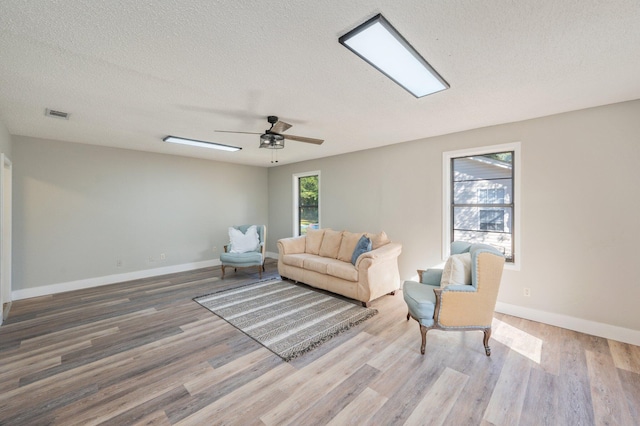 living room featuring a textured ceiling, hardwood / wood-style flooring, and ceiling fan