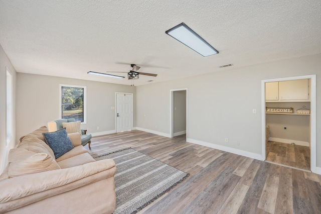 living room featuring ceiling fan, hardwood / wood-style floors, and a textured ceiling