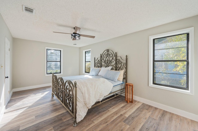 bedroom featuring ceiling fan, hardwood / wood-style floors, and a textured ceiling