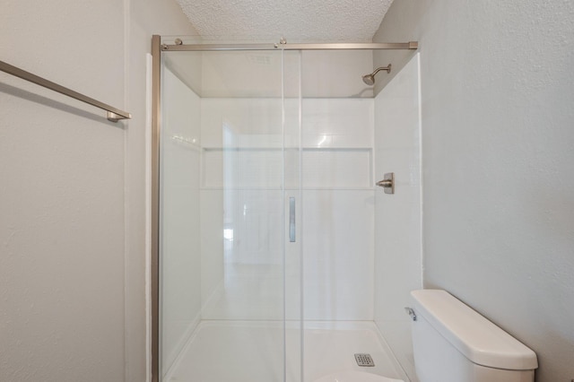 bathroom featuring an enclosed shower, a textured ceiling, and toilet