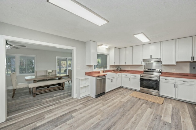 kitchen featuring white cabinetry, sink, wooden counters, a textured ceiling, and appliances with stainless steel finishes