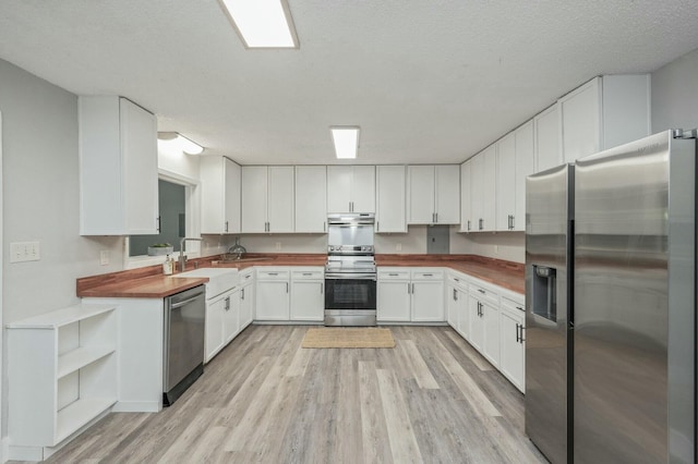 kitchen featuring sink, a textured ceiling, white cabinetry, butcher block counters, and stainless steel appliances