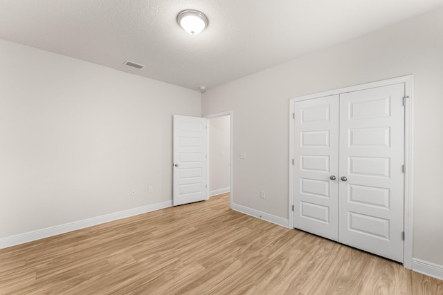 unfurnished bedroom featuring light hardwood / wood-style floors, a textured ceiling, and a closet