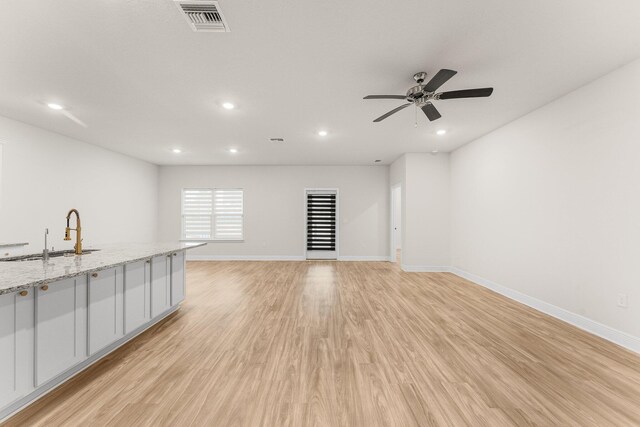 unfurnished living room featuring ceiling fan, sink, and light hardwood / wood-style flooring