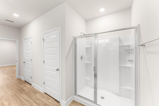 bathroom featuring wood-type flooring and a shower with shower door