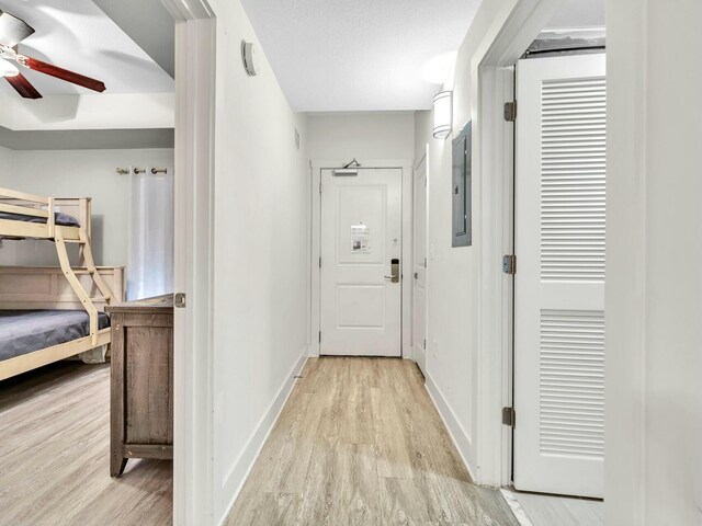 corridor with electric panel and light wood-type flooring