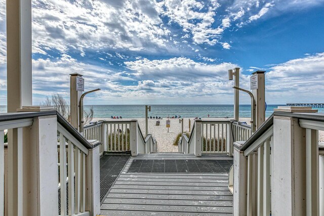 wooden terrace with a water view and a view of the beach