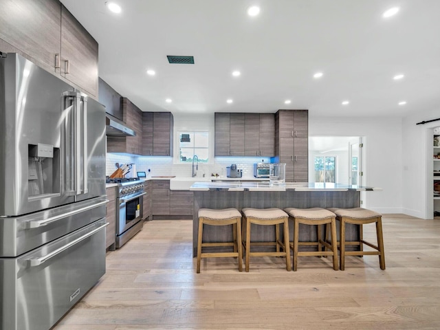 kitchen featuring a kitchen island, modern cabinets, high quality appliances, a breakfast bar area, and light countertops