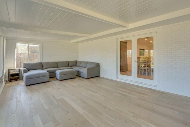 unfurnished living room featuring french doors, light wood finished floors, brick wall, wooden ceiling, and beamed ceiling