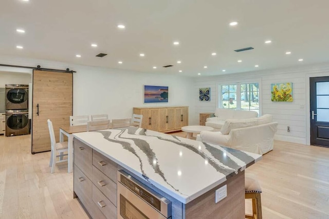 kitchen with a breakfast bar, a barn door, a large island, and stacked washer / dryer