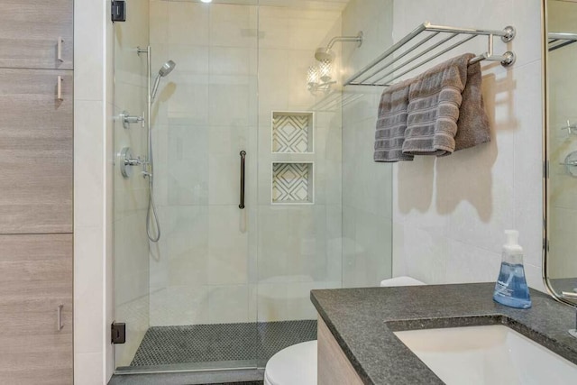 full bath with toilet, a stall shower, vanity, and tile walls