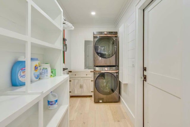 laundry room with cabinet space, light wood finished floors, stacked washer / drying machine, crown molding, and recessed lighting